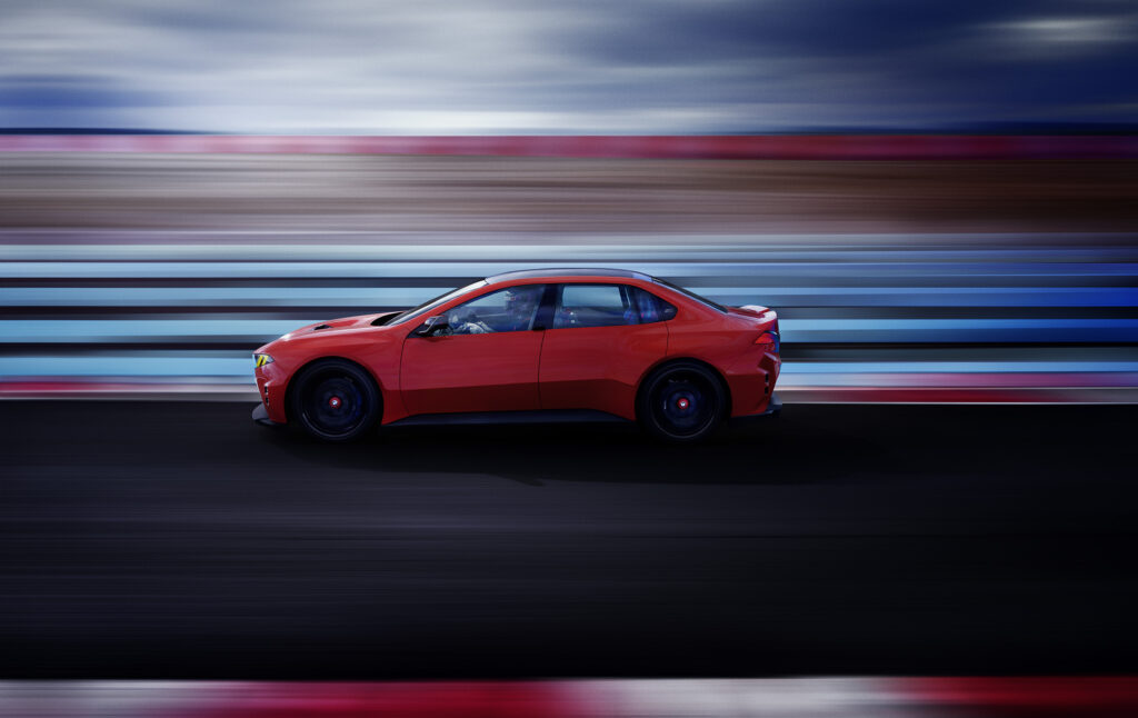 BMW M Concept Neue Klasse en color Monza Red visto de perfil en pista, destacando su diseño deportivo, aerodinámica y enfoque de alto desempeño.