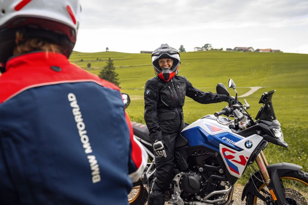 Motociclistas usando equipamiento Rallye GORE-TEX de BMW Motorrad en una ruta al aire libre, diseñado para conducción adventure con protección y comodidad.