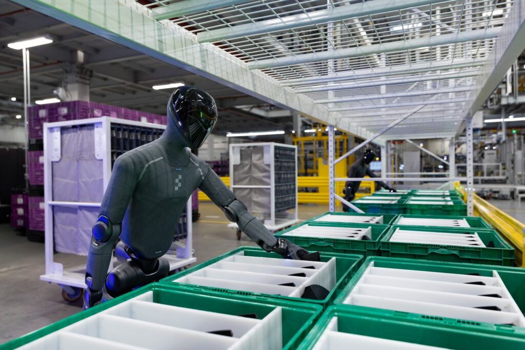 Robot humanoide Figure 03 realizando tareas de secuenciación logística en BMW Group Planta Spartanburg, junto a contenedores de piezas en el área de producción.
